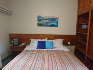 een bed met twee blauwe kussens in een slaapkamer bij Galápagos ApartHotel in Ilhabela