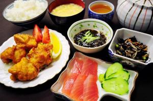 una mesa cubierta con platos de comida con sushi y verduras en Pension Orange Box en Isla Miyako