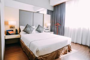 a large white bed in a room with a window at Hotel Granada Johor Bahru in Johor Bahru