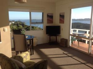 uma sala de estar com uma televisão e uma varanda em Panorama Heights Apartment em Paihia