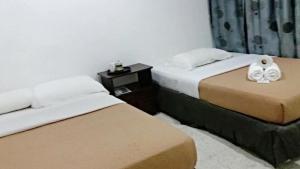 two beds in a hotel room with towels on them at CasaPelindung Guesthouse in Kuantan