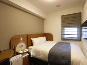 a hotel room with a bed and a window at Hotel Sunroute Sopra Kobe Annesso in Kobe