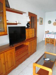una sala de estar con TV en un centro de entretenimiento de madera en Sea View Apartment, en Torrevieja
