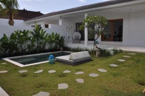 een achtertuin met een zwembad en een bed in het gras bij Villa Enjoy in Canggu