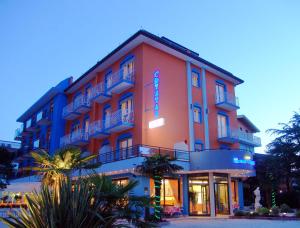 a red building with a blue sign on it at Hotel Crystal in Caorle