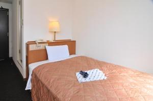a hotel room with a bed with a pair of shoes on it at Yawatajuku Dai-ichi Hotel in Ichihara