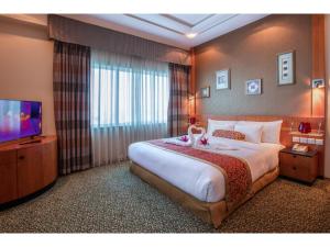 a hotel room with a large bed and a television at Gulf Court Hotel in Manama