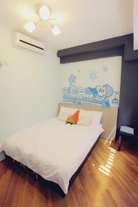 Un dormitorio con una cama blanca con un cuadro en la pared. en FUNDI Hotel, en Tainan