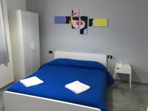 een slaapkamer met een blauw bed en 2 witte handdoeken bij Interno 10 in Siracusa