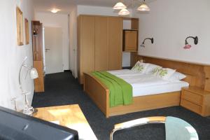 ein Schlafzimmer mit einem Bett mit einer grünen Decke darauf in der Unterkunft Hotel Torgauer Brauhof in Torgau