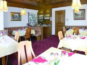 a dining room with white tables and chairs with pink napkins at Pension Tannenhof in Laces