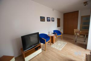 a living room with a flat screen tv and blue chairs at Kulturne Centrum Bardejov in Bardejov