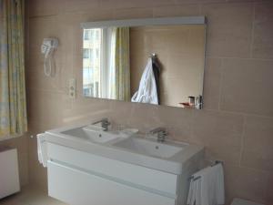 La salle de bains est pourvue d'un lavabo blanc et d'un miroir. dans l'établissement Gastenkamers Centersuites, à Oostduinkerke