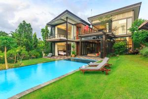 a house with a swimming pool in front of a house at Omah Sabin Villa East in Canggu