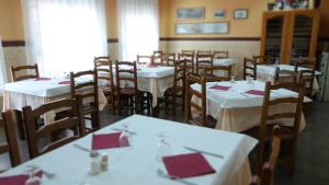 Un comedor con mesas y sillas blancas con servilletas rojas. en Hostal Restaurante La Masía, en Villareal
