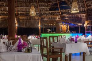 a dining room with white tables and chairs and lights at Zanzibar Queen Hotel in Matemwe +37 photos