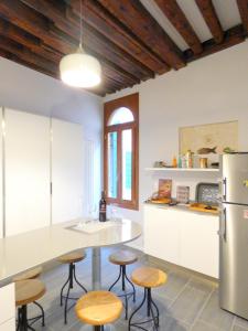 a kitchen with a counter and stools and a refrigerator at Ca' Neldo - VeniseJeTAime in Venice