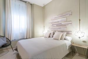 a bedroom with a large white bed and a window at Apartamentos Diaber San Leandro in Seville