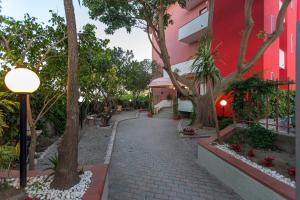 a brick walkway next to a red building with trees at Hotel Villa Susy in Davoli