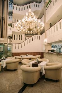 eine große Lobby mit Stühlen und einem Kronleuchter in der Unterkunft Grand Hotel Sole in Nitra