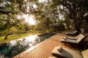 a wooden deck with chairs and a swimming pool at Rukiya Safari Camp in Hoedspruit