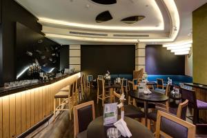 a restaurant with tables and chairs and a bar at Raintree Rolla Hotel in Dubai