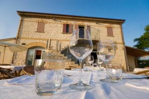 cuatro copas de vino sentadas en una mesa frente a un edificio en Agriturismo Casa Rossi di Paolo Rossi en Numana