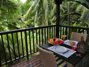 a table with a bowl of fruit and drinks on a balcony at Hillside Retreat in Baie Lazare Mahé