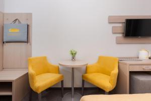 Pokój z 2 żółtymi krzesłami i stołem w obiekcie Solaris w Pobierowie