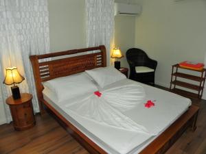 Una cama con sábanas blancas y flores rojas. en Hillside Retreat en Baie Lazare Mahé