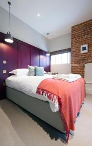 a bedroom with a large bed with a red blanket on it at The Coach House in Potton