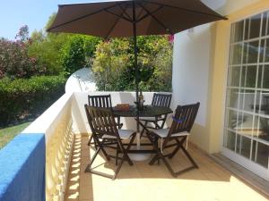 a table with two chairs and an umbrella on a porch at Praia da Luz Apartments in Luz