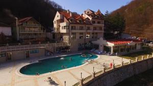 ein Schwimmbecken mit Menschen darin vor Gebäuden in der Unterkunft Hotel Kopaonik Lukovska Banja in Lukovo