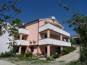 a pink and white building on the side of a street at Apartments Murgic in Krk