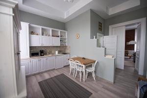 a kitchen with white cabinets and a wooden table at Apartament Maria in Timişoara