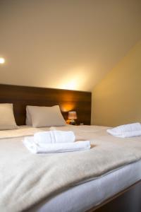 Dos camas en una habitación con toallas blancas. en Penzion Oaza en Luhačovice