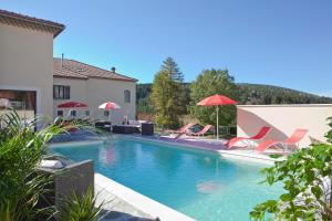 a swimming pool with red chairs and umbrellas at hotel des Sapins in Lanarce