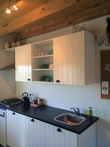 uma cozinha com armários brancos e um lavatório em Boerengastenverblijf De Kromme Rijn em Cothen