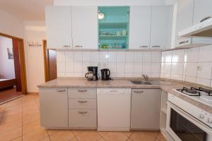 a kitchen with white cabinets and a sink at Apartment Doris in Kaštela