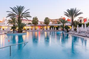 a large swimming pool with palm trees and buildings at Barut B Suites in Side