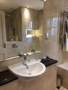 a bathroom with a sink and a mirror and a tub at New House Country Hotel in Cardiff +40 photos