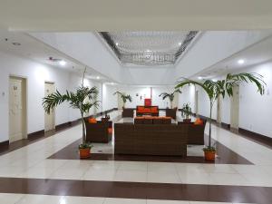 a lobby with couches and palm trees in it at Apartemen MTC in Manado