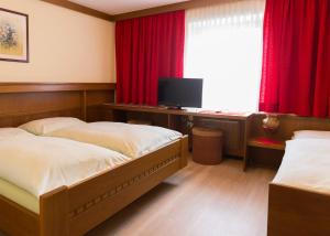 a bedroom with two beds and a desk with a television at Gasthof Mandorfer in Hörsching