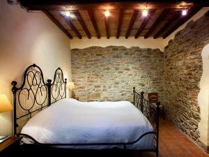 a bedroom with a white bed in a brick wall at Relais La Torre in Chiassa Superiore