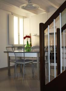 una mesa de comedor con sillas y un jarrón de flores en Appartamento Borghetto, en Comacchio