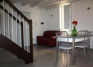 - une salle à manger avec une table, des chaises et un canapé rouge dans l'établissement Appartamento Borghetto, à Comacchio