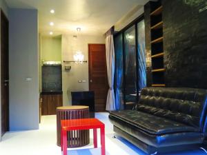 a living room with a black leather couch and a red stool at Pony Hill Villa in Bophut