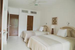 two beds in a room with white walls at Las Villas Akumal in Akumal