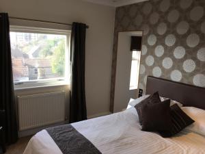a bedroom with a bed with a window and a bedspread at Queenswood Hotel in Weston-super-Mare