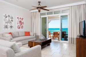 a living room with a couch and a tv at Alexandra Resort- All Inclusive in Grace Bay